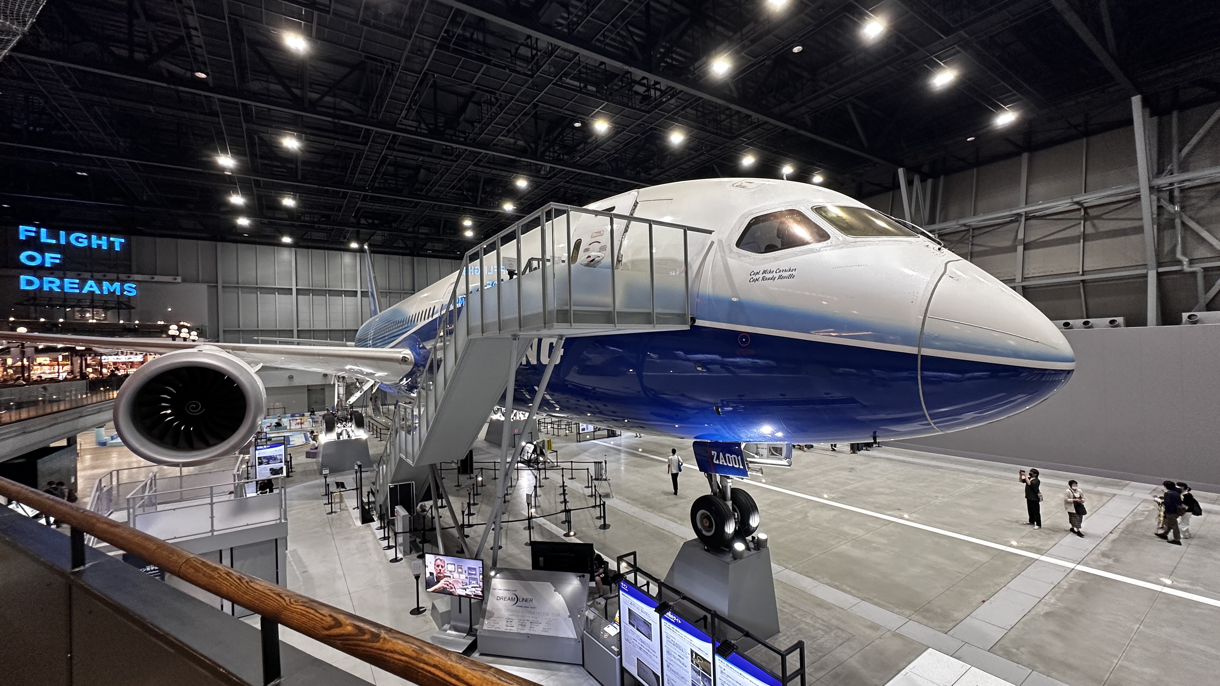 從二樓看 787 的機頭，左側牆上寫著 FLIGHT OF DREAMS，登機梯接在機身側面