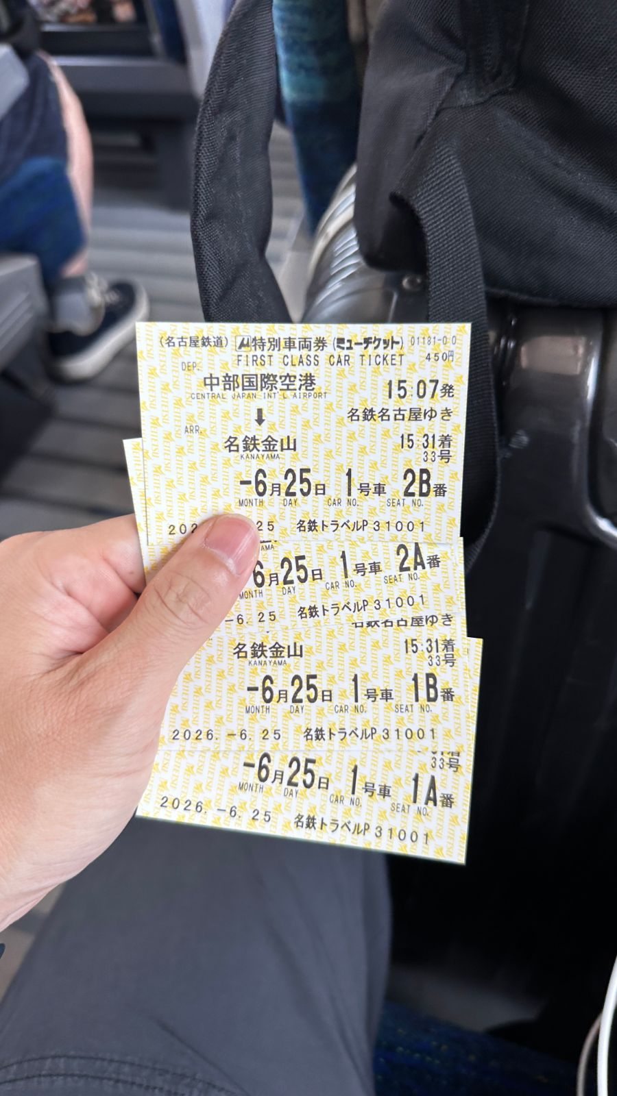 手上拿著四張名鐵特別車廂券，黃色票面印著中部國際機場到名鐵金山的班次與座位號碼