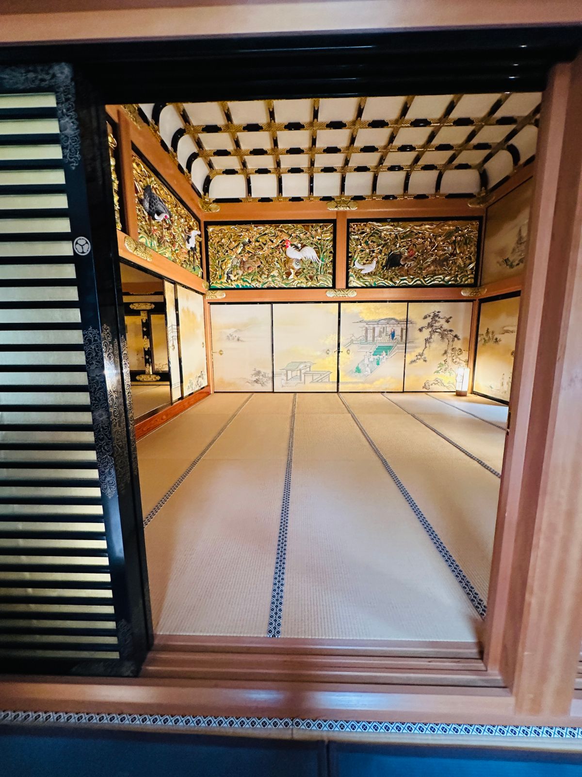 本丸御殿內部，金箔襖繪與雕花欄間圍著鋪滿榻榻米的房間，天花板是格狀的木造結構