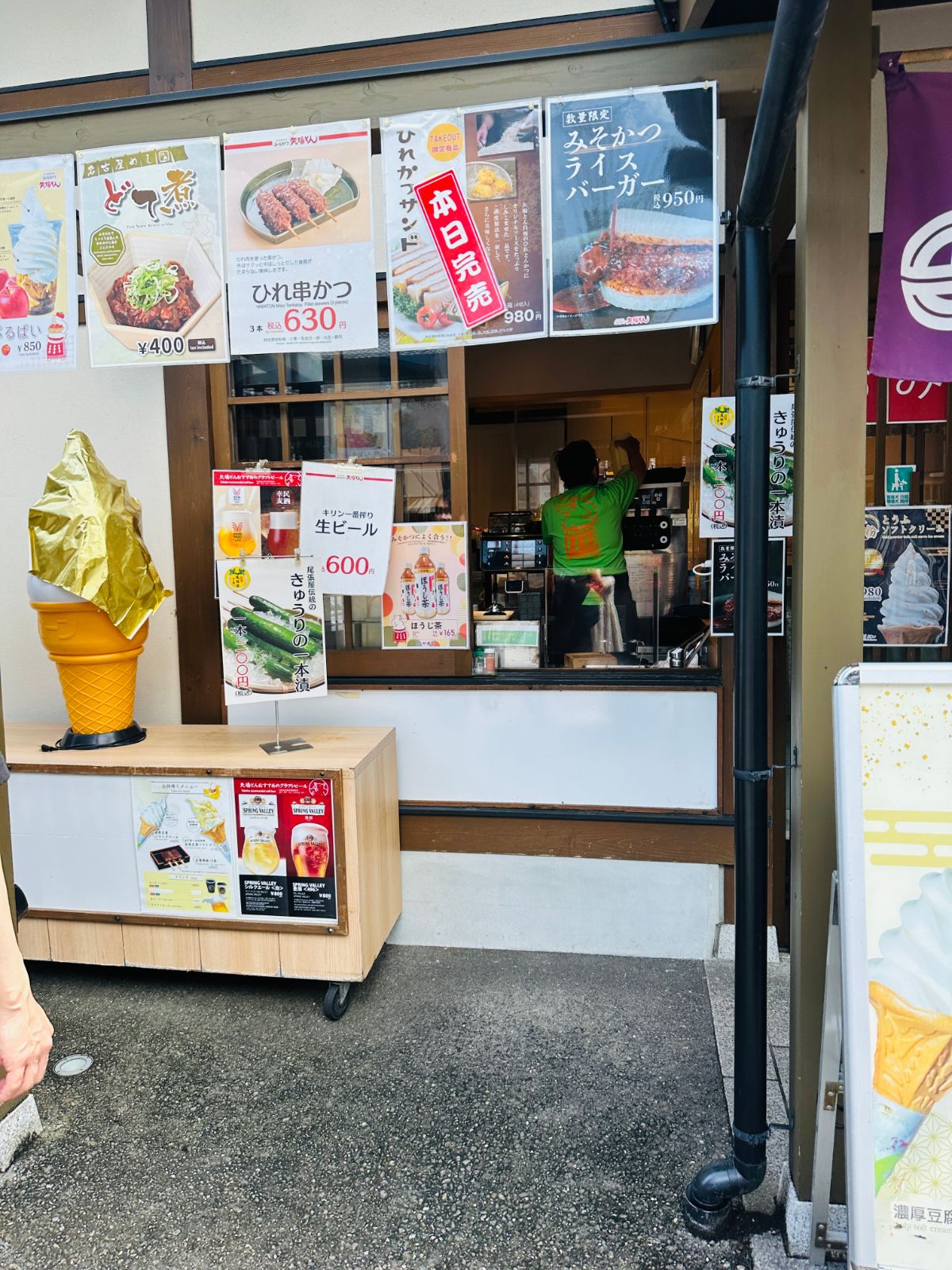 城內的小吃攤，木造窗口貼滿味噌豬排、串炸與霜淇淋的海報，左側立著金色的霜淇淋模型