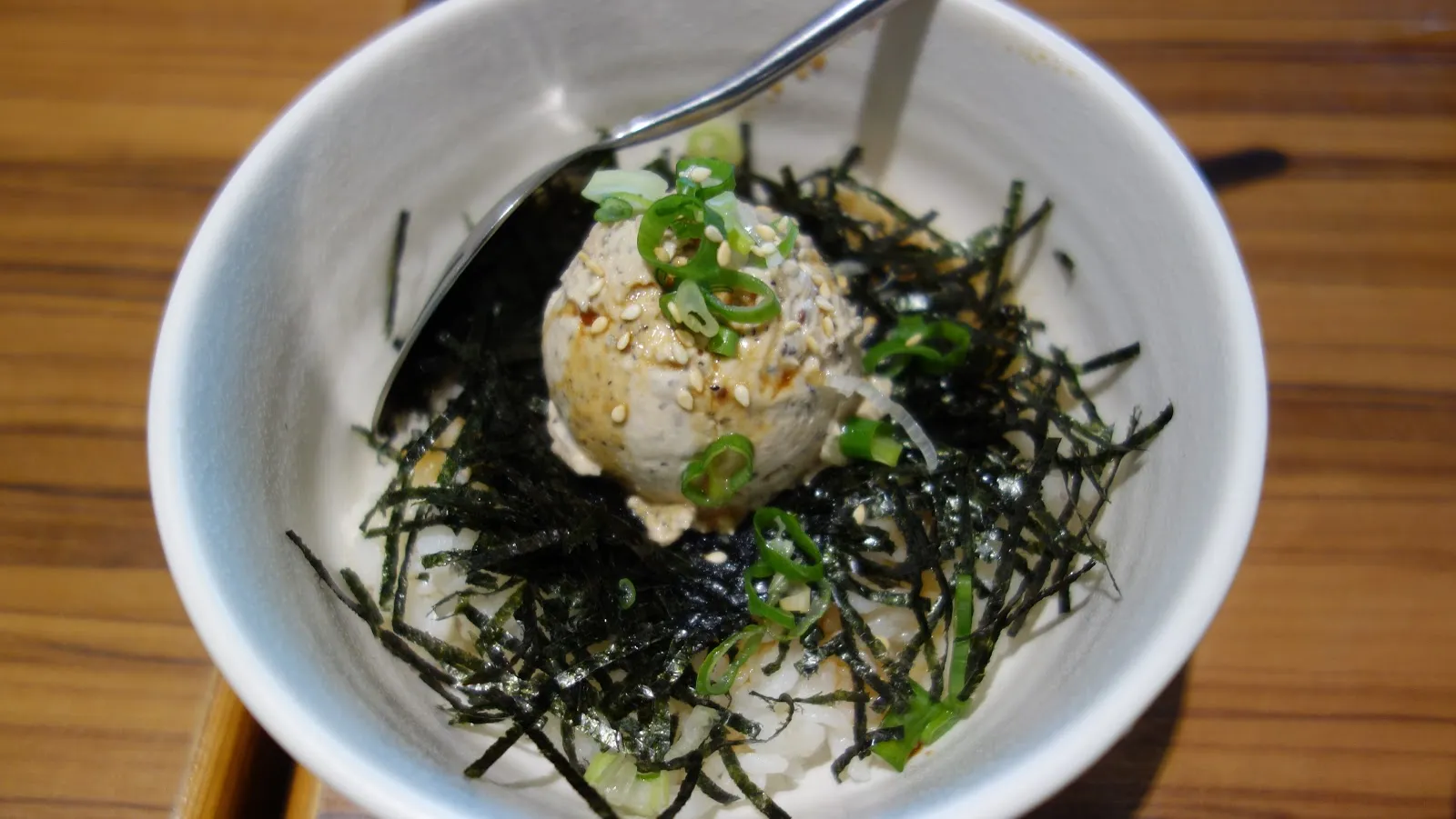 白色小碗裡盛著一球飯，上面蓋滿海苔絲與蔥花，插著一支湯匙