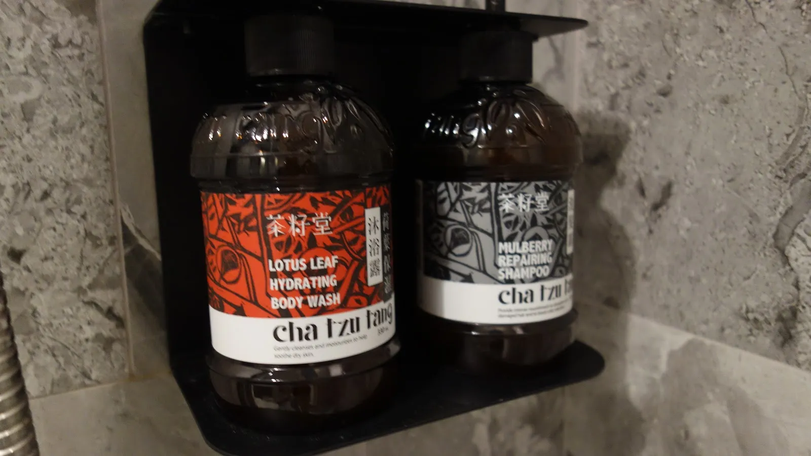 檯面上兩瓶茶籽堂的沐浴乳與洗髮乳，橘色與灰色標籤上印著 cha tzu tang