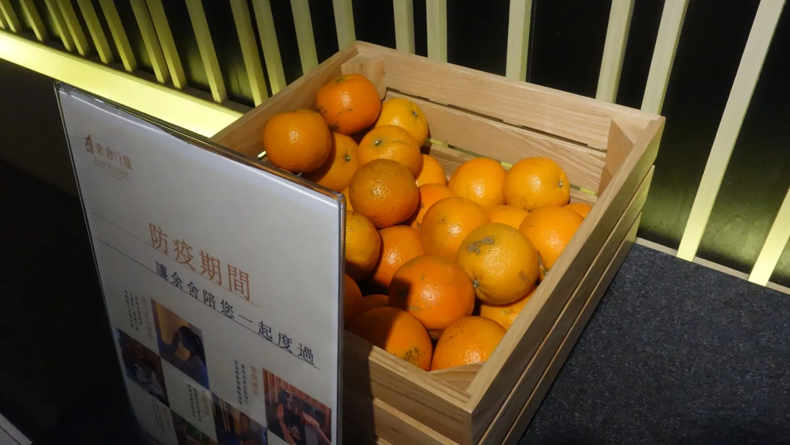 木箱裡裝滿柳橙，旁邊立著飯店的防疫期間告示牌
