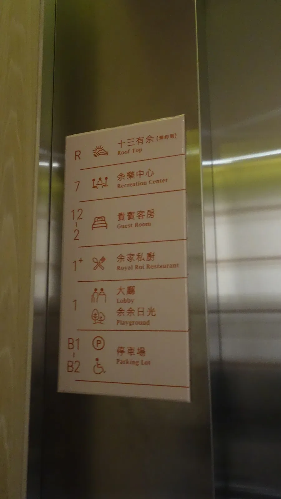 電梯旁的樓層指示牌，紅字標示 R 頂樓、7 樓娛樂中心、2 到 12 樓客房、1 樓大廳與余舍私廚，以及 B1、B2 停車場