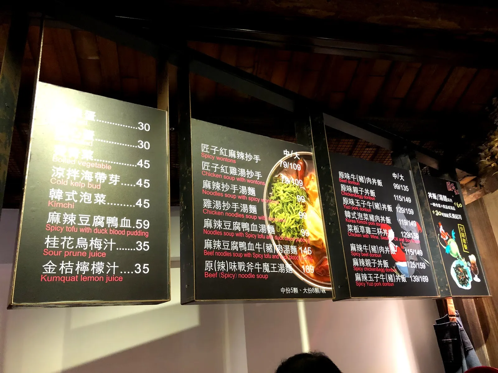 店內牆上的一整排燈箱菜單，列著抄手、涼拌小菜與麻辣豆腐鴨血 59 元、桂花烏梅汁 35 元等品項