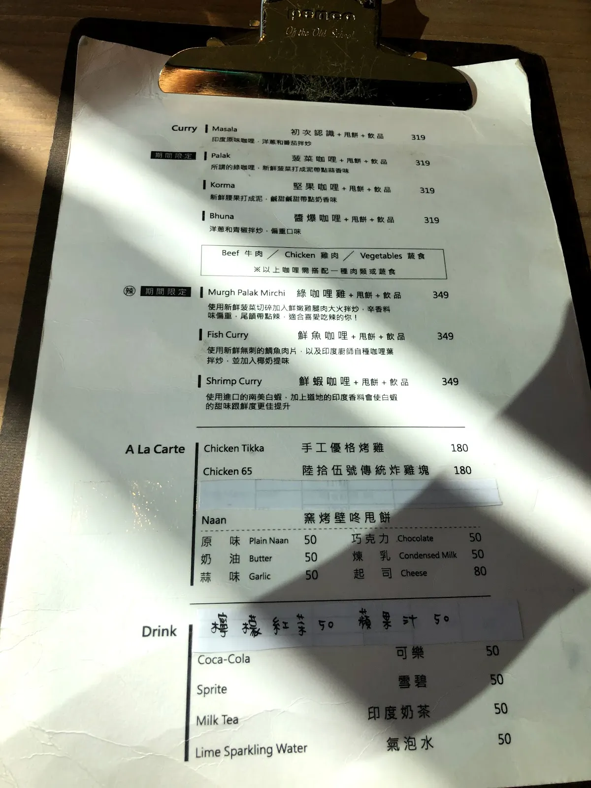板夾上的咖哩菜單，Curry 主餐 319 到 349 元，單點的手工優格烤雞 180 元，Naan 原味 50 元到起司 80 元，下方是飲料區