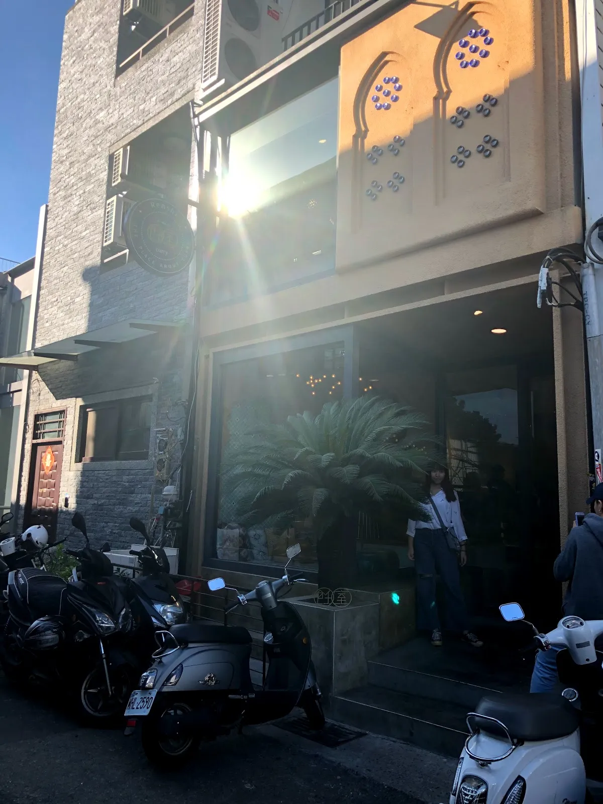 飪室咖哩的店門外觀，灰磚立面的二樓有花磚裝飾，一樓是整片玻璃門面，門口停著機車