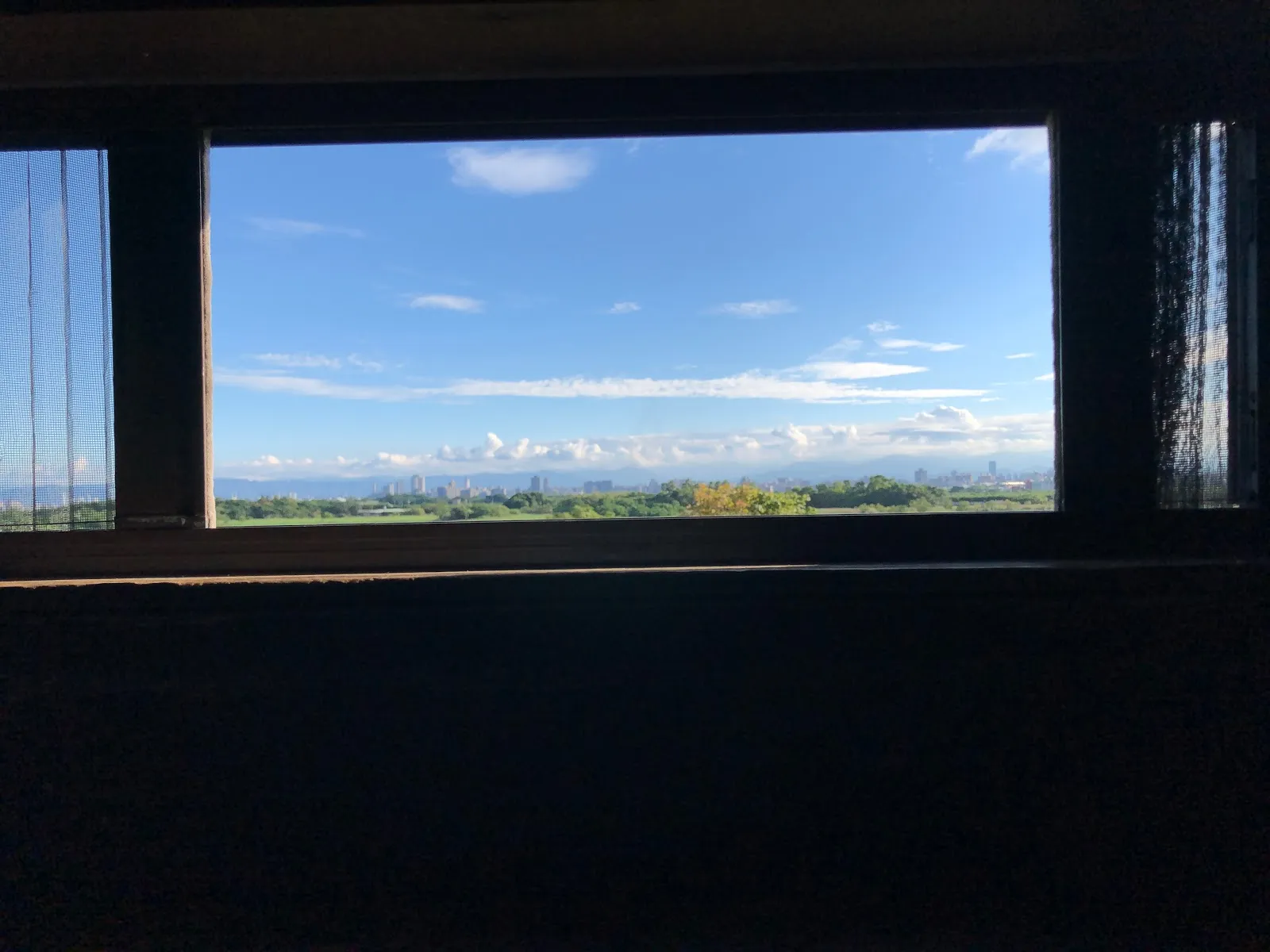 從賞鳥小屋的橫向長窗往外看，窗框框住一整片藍天與遠方的濕地