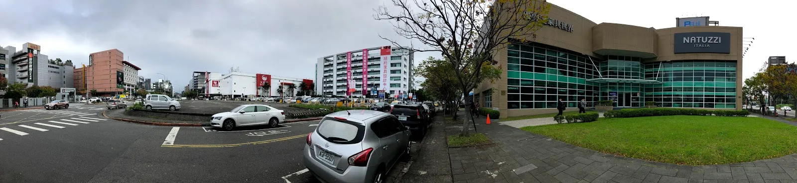 停車場的另一側，遠方是玻璃帷幕的商場建築與周邊住宅