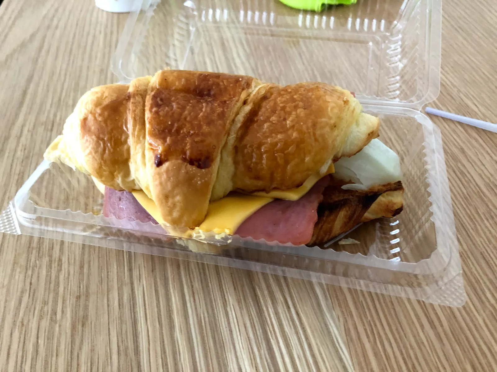透明餐盒裡的可頌三明治，可頌夾著火腿、起司與煎蛋