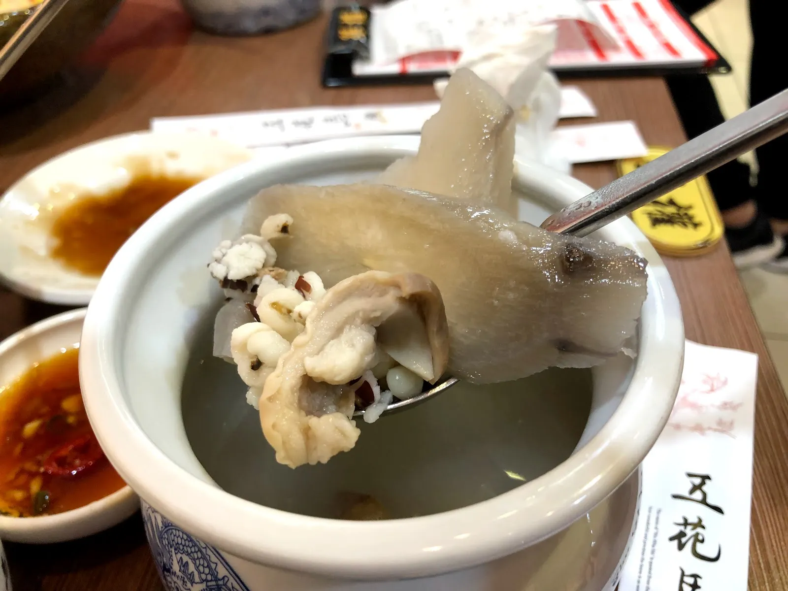 白色湯盅裡的湯品，筷子夾起一塊麵皮，桌上還放著沾醬碟