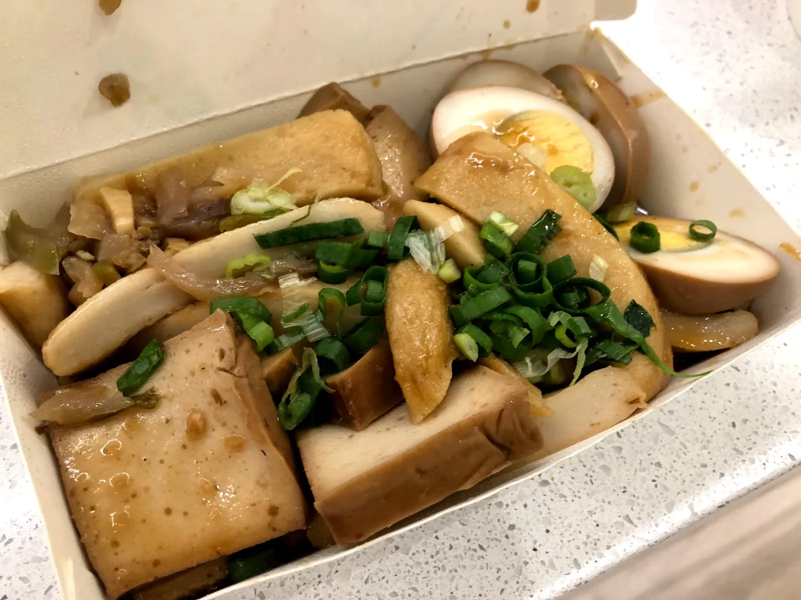 白色紙盒裡的滷味，豆腐、米血、豆干與滷蛋淋著醬汁，撒上大量蔥花