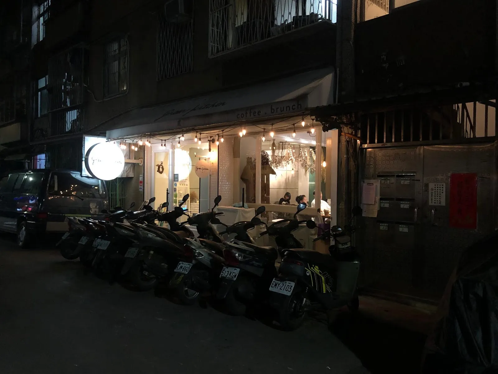 夜晚的巷弄街景,一整排機車停在亮著燈的店家門前