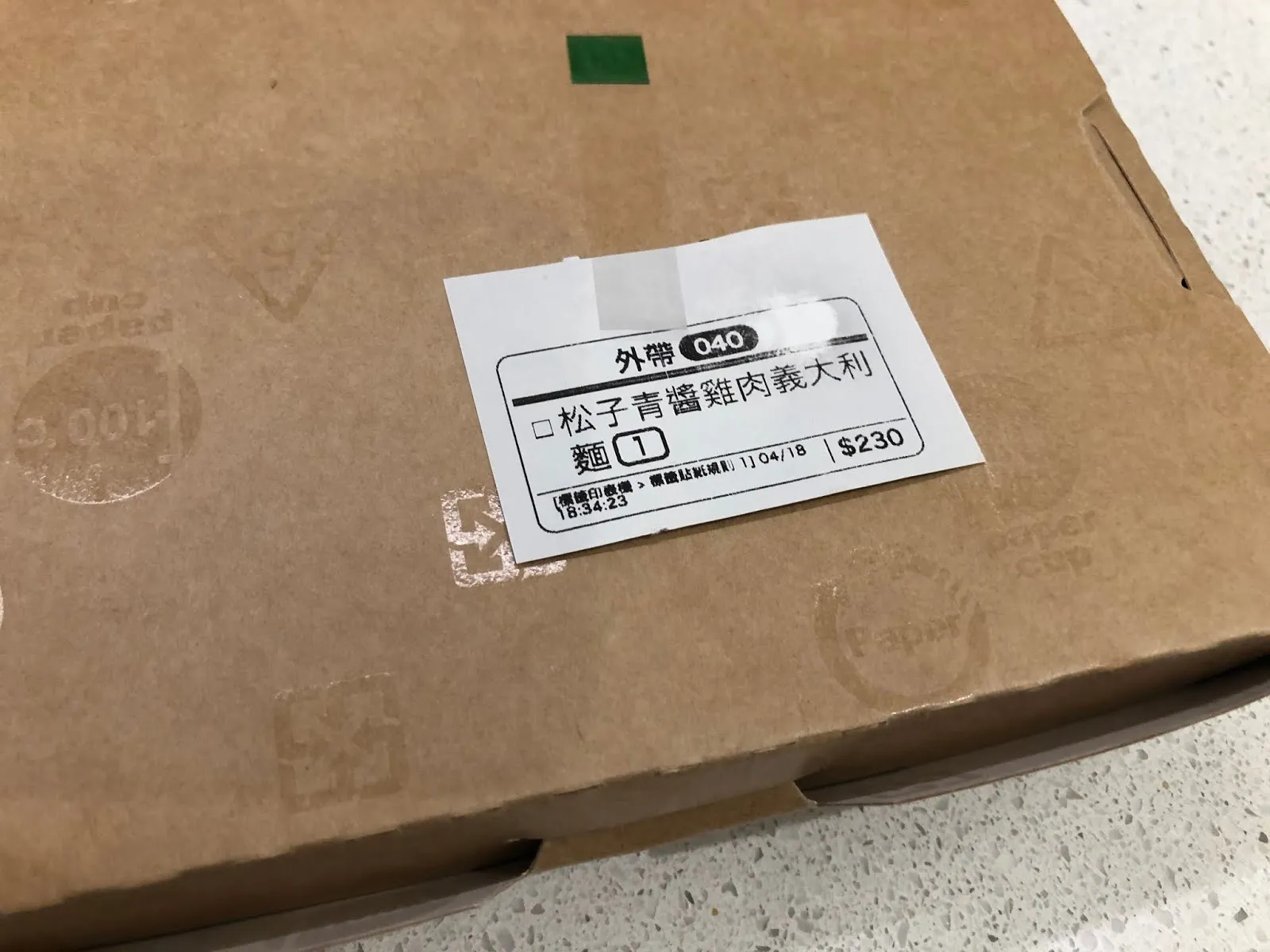 牛皮紙外帶袋上貼著點餐標籤,寫著松子青醬雞肉義大利麵 230 元