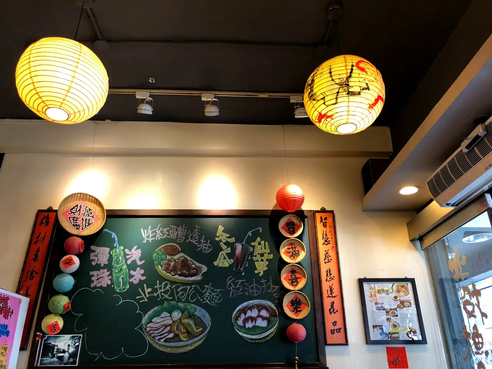店內牆面的黑板手寫菜單，畫著餐點插圖與招牌品項，兩側懸著黃色紙燈籠