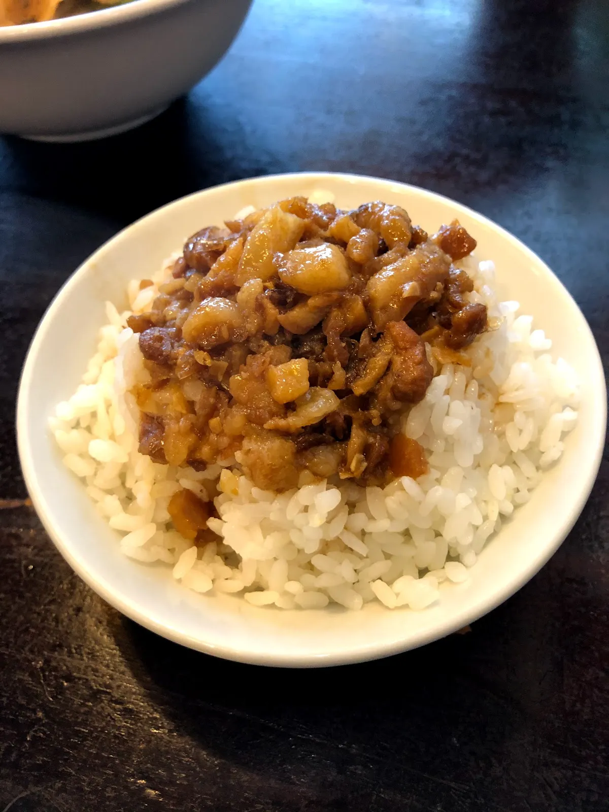 白色小碗裡的魯肉飯，滷得深褐的肉燥淋在白飯上