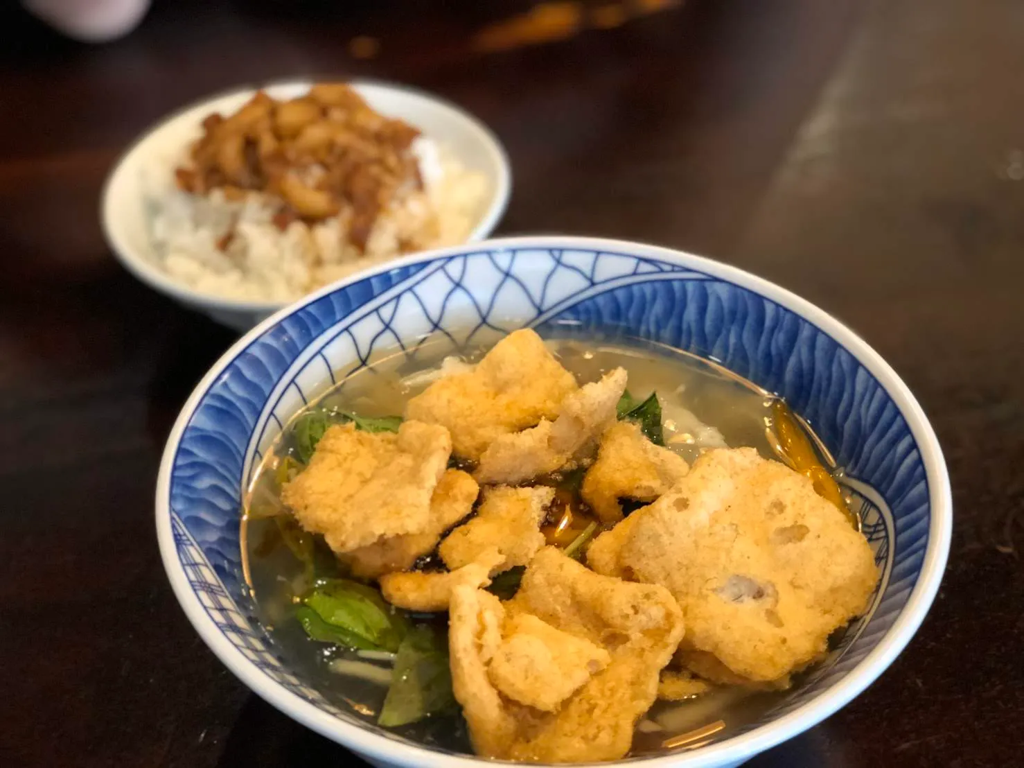 桌上並排的一碗魯肉飯與一碗魷魚羹湯，羹湯裡浮著炸豆皮與青菜