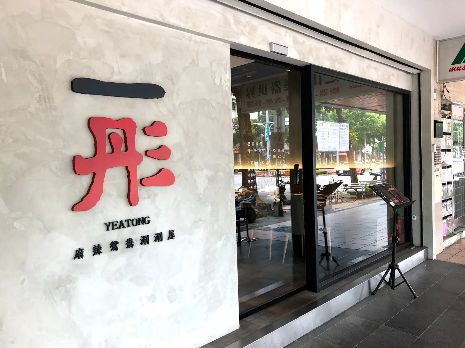 一彤的店門外觀,白色大理石紋牆面嵌著紅色的「一彤 YEATONG」字樣與麻辣鴛鴦涮涮屋的副標