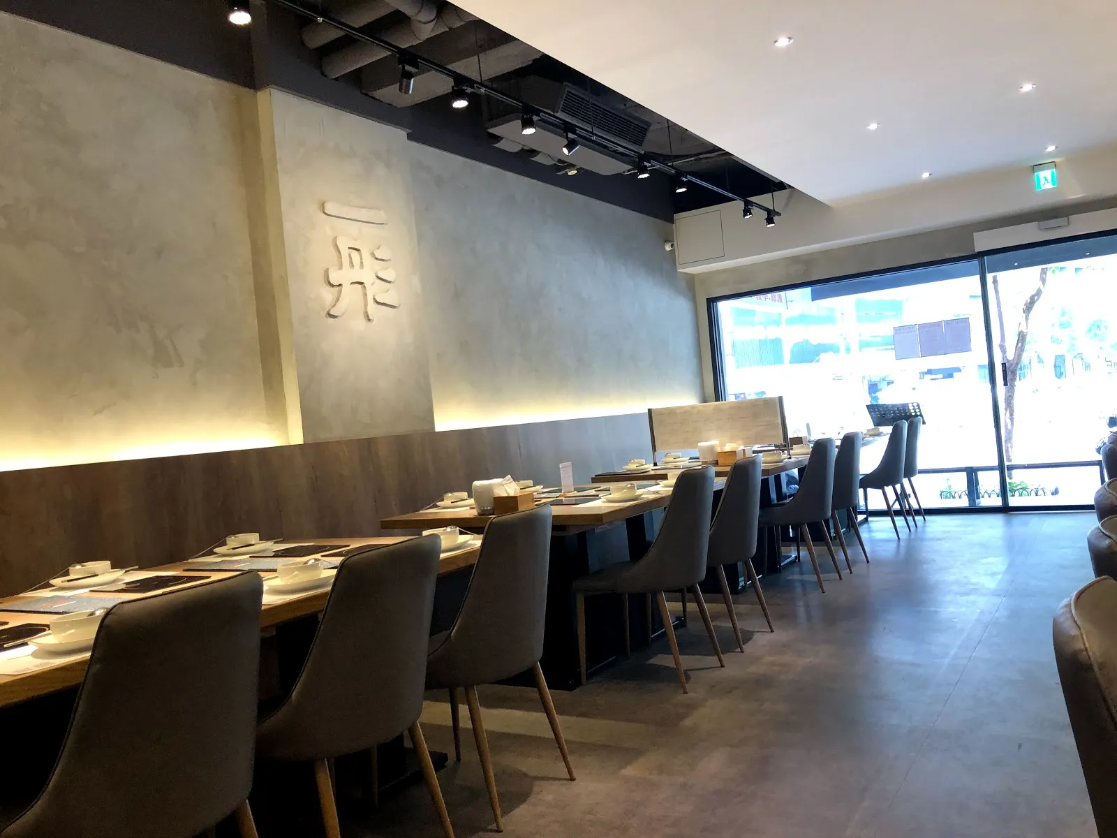 店內用餐區,一長排單人座沿著落地窗排開,每個位子都有獨立爐口,牆上是「一彤」的白色浮雕字