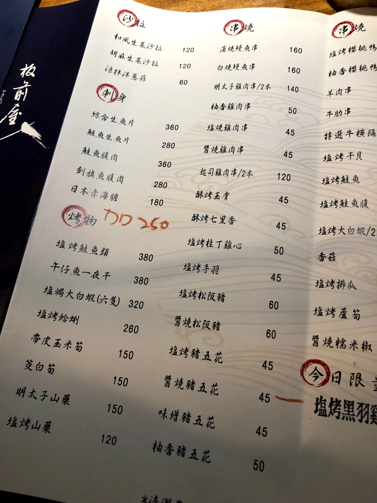 板前屋的紙本菜單，白底紅框分成飯類、丼飯與鹽烤、醬烤串燒的價目，右下角標著今日限定的鹽烤黑羽雞翅