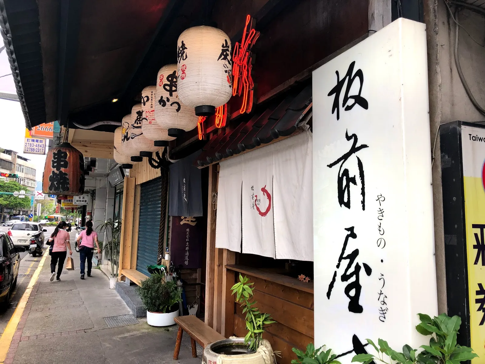板前屋的店門外觀，白色暖簾上寫著「板前屋」與「やきもの・うなぎ」，屋簷下掛著白色與紅色的燈籠
