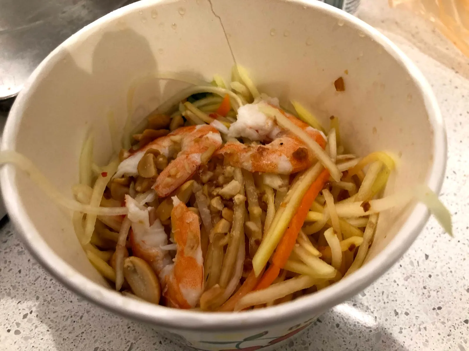 紙碗裡的青木瓜沙拉，木瓜絲與紅蘿蔔絲拌著蝦仁與花生米