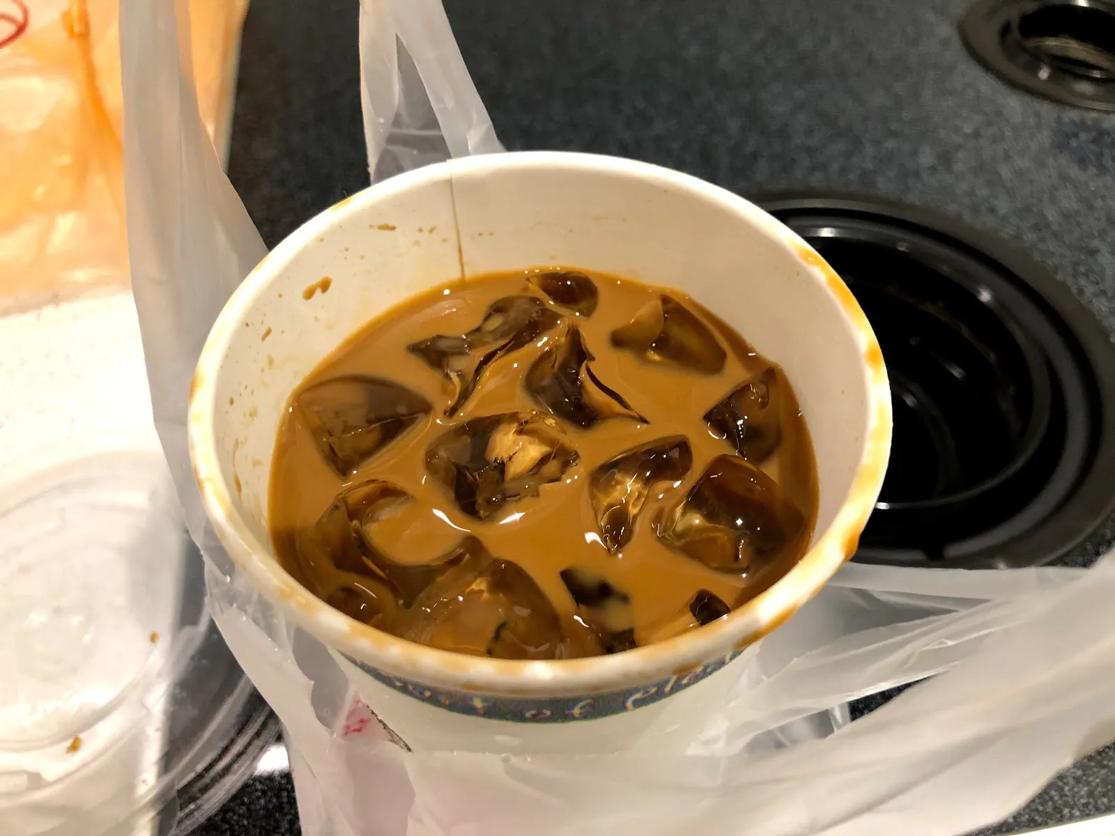 塑膠杯裝的越式冰咖啡，深褐色的咖啡牛奶裡浮著冰塊，放在廚房檯面上