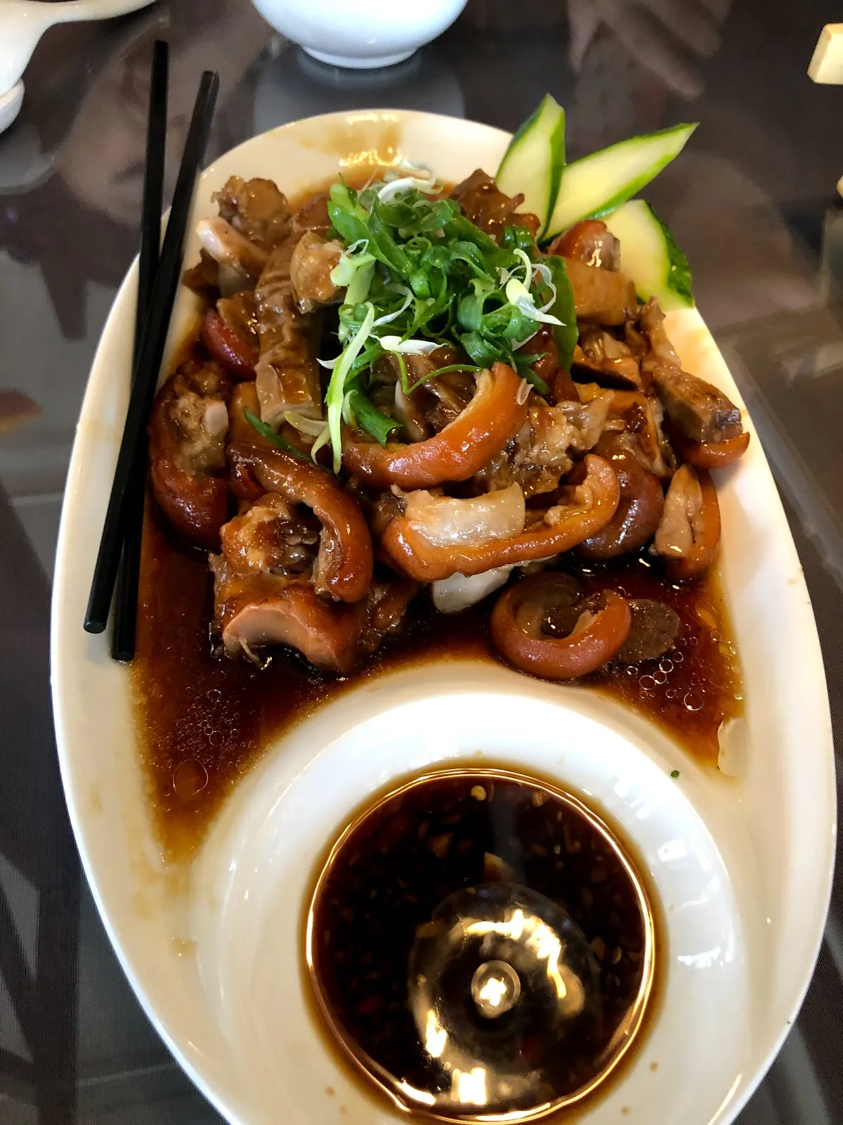 白瓷盤裡的滷味拼盤，深褐色的滷肉與豆皮堆成一座，上面撒著青蔥絲與小黃瓜片，中央的碗裝著滷汁