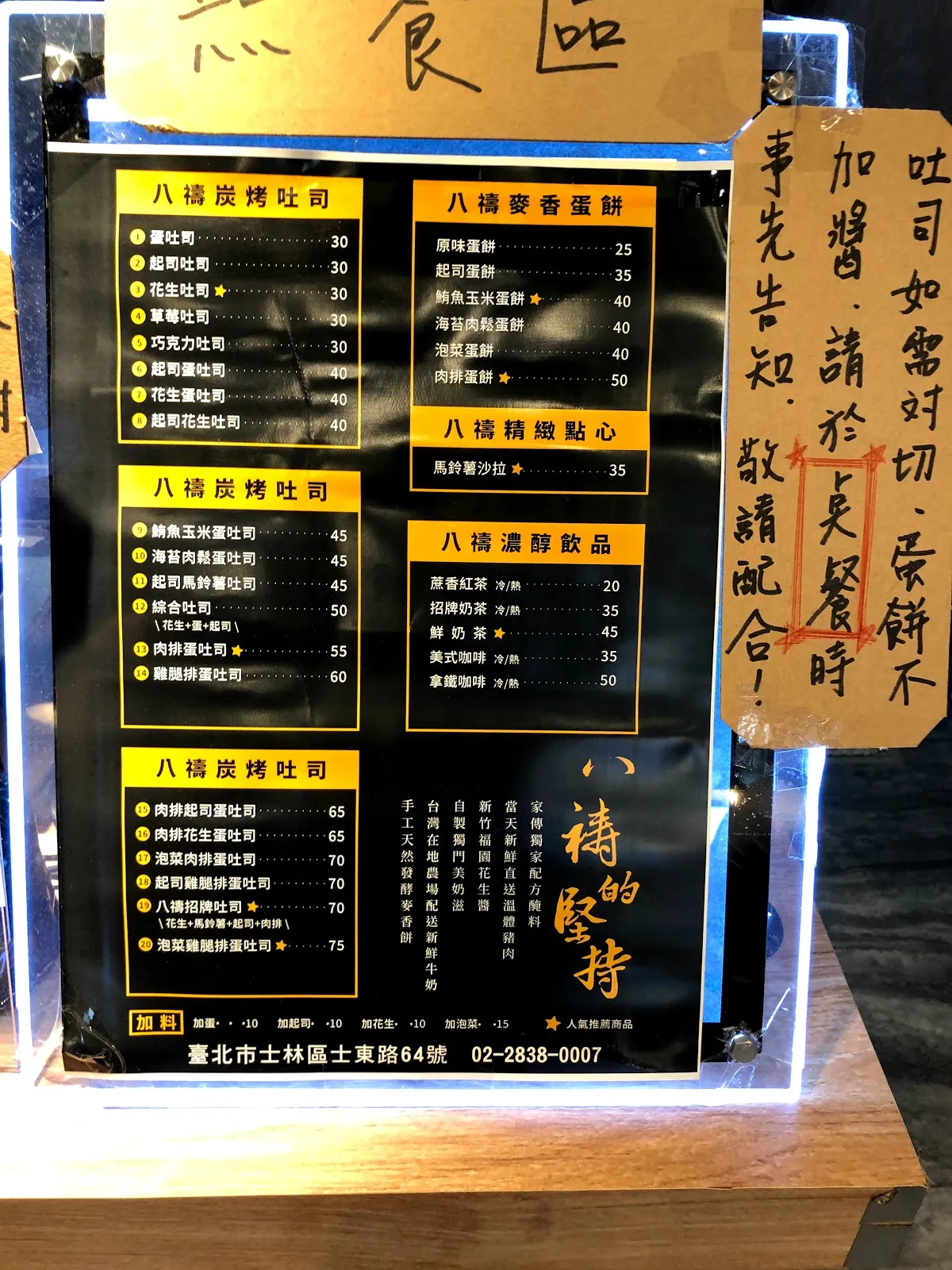 店內的黑底黃字菜單，炭烤吐司從蛋吐司 30 元到雞腿排吐司 60 元，蛋餅類 25 到 50 元，飲品 20 到 50 元，右側貼著手寫告示提醒吐司如需對切或不加醬請於點餐時告知