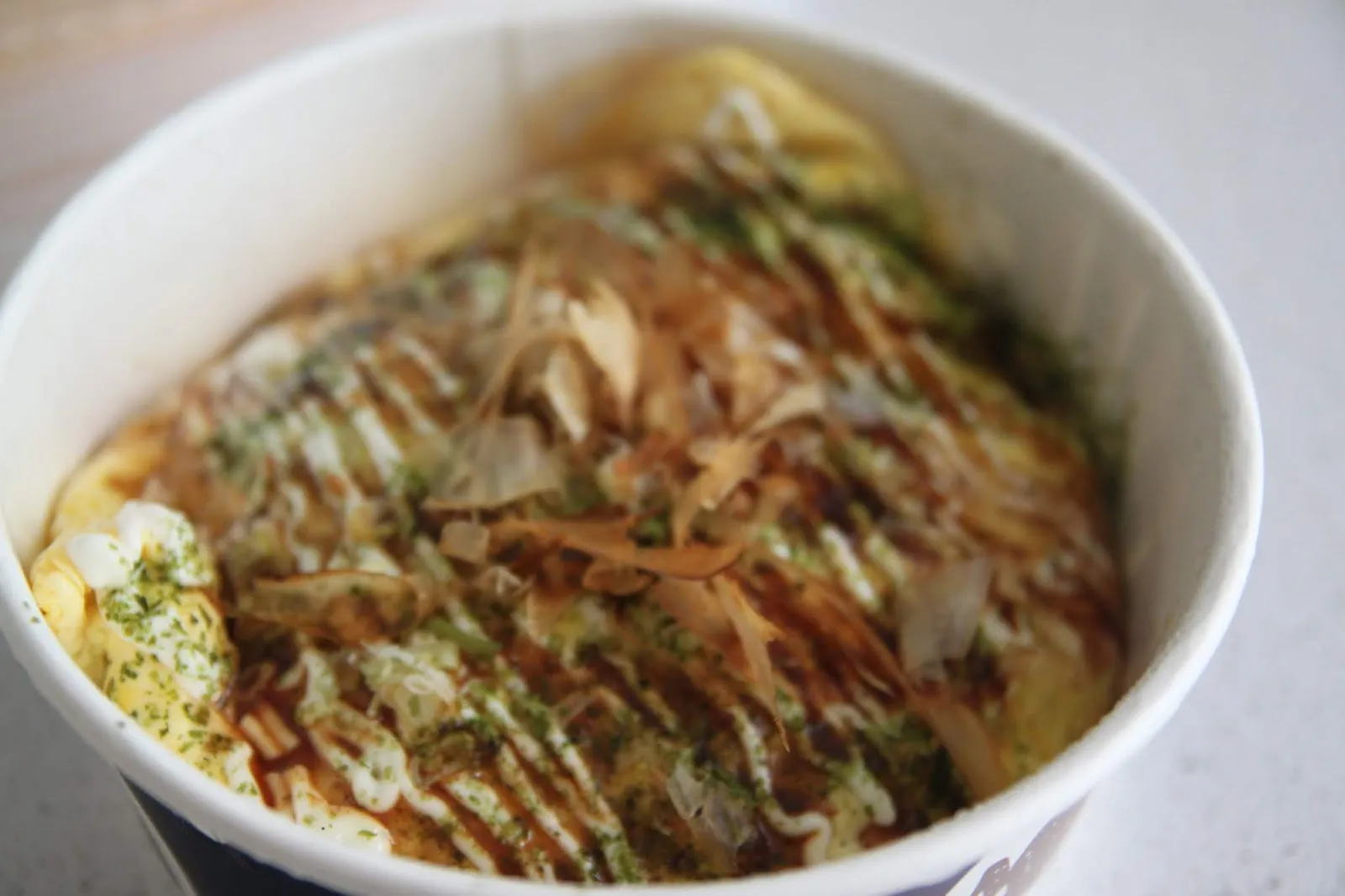 大阪燒牛五花炒麵,表面鋪滿柴魚片與海苔粉,淋上交錯的照燒醬與美乃滋