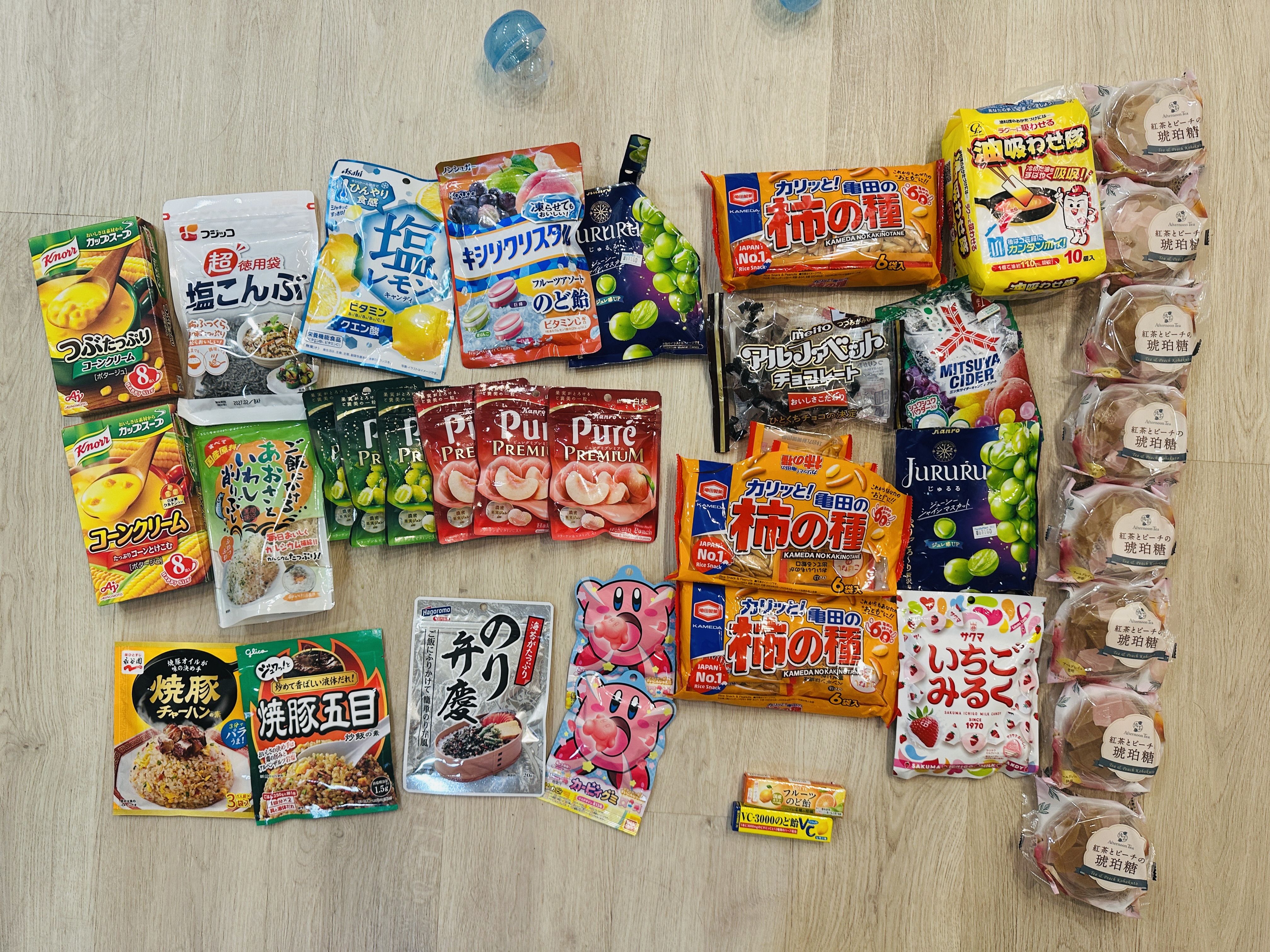 買回來的零食與調理包，有柿種米果、軟糖、鹽昆布、玉米濃湯粉、燒豚炒飯調理包、卡比獸圖案的零食，以及右側整排真空包裝的和菓子