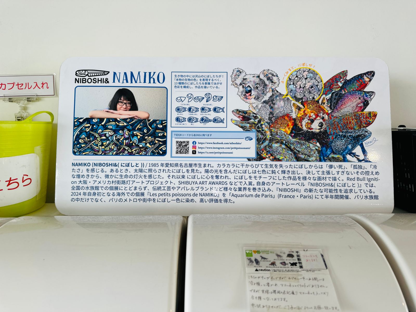 藝術家 NAMIKO 的介紹看板，左側是本人照片，右側是她以無尾熊、小熊貓等動物為題的彩色點描畫作