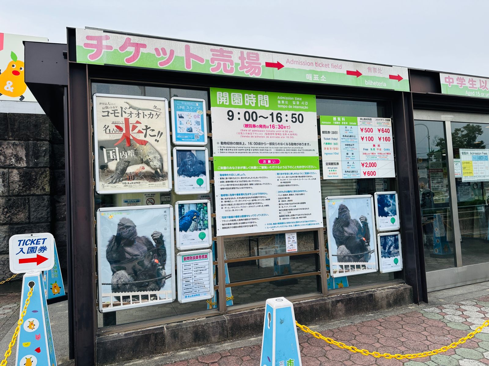 售票口外觀，綠底白字的「チケット売場」招牌下貼著營業時間 9:00 到 16:50 與各項票價，左側是科摩多巨蜥的宣傳海報