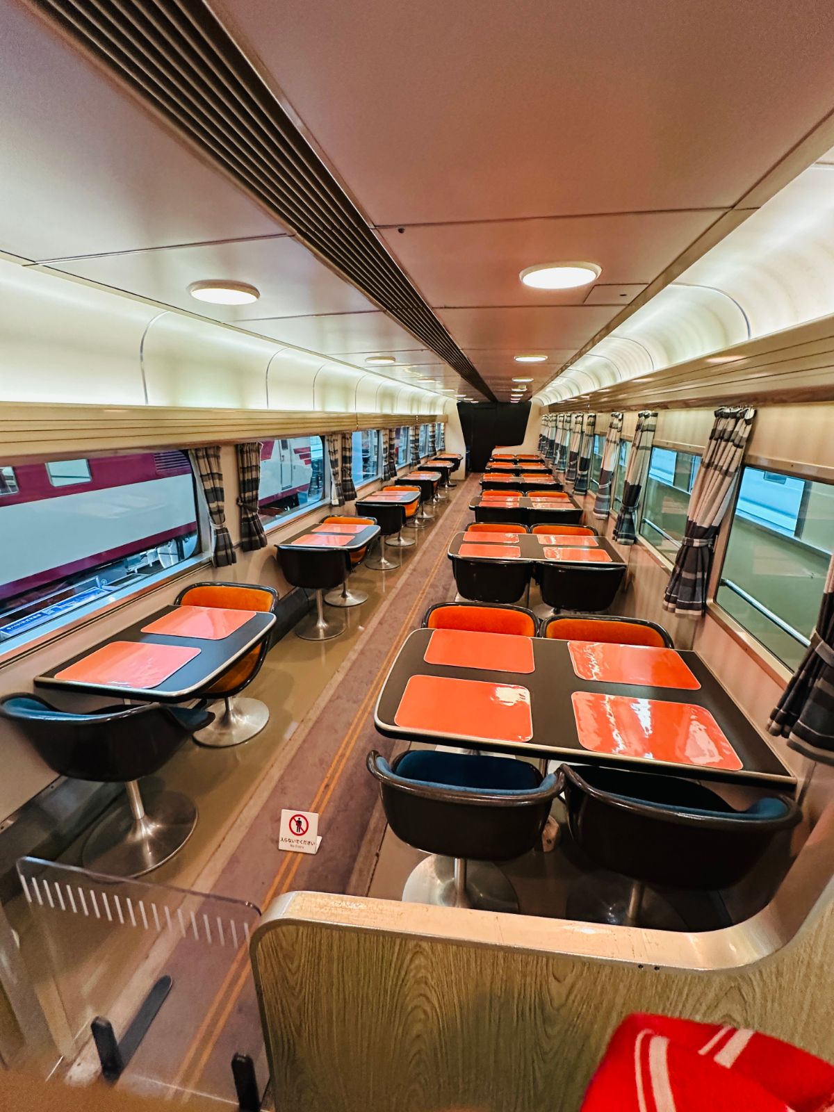 復古餐車車廂，橘色桌墊的方桌兩側配著黑色圓椅，木質天花板與暖黃燈光