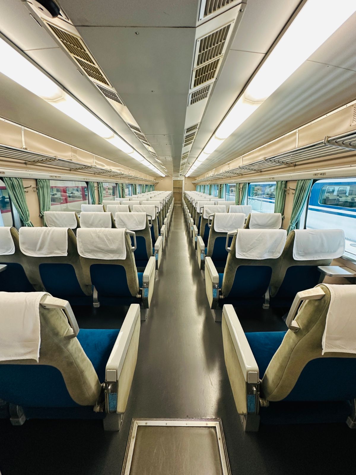 藍色絨布座椅的舊型特急車廂內部，椅背都鋪著白色頭巾，車窗掛著淺綠色窗簾